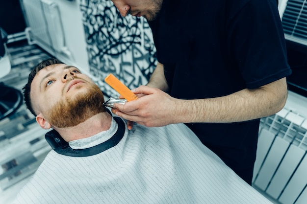 Barber, der bärtigen Mann mit Rasiermaschine trimmt