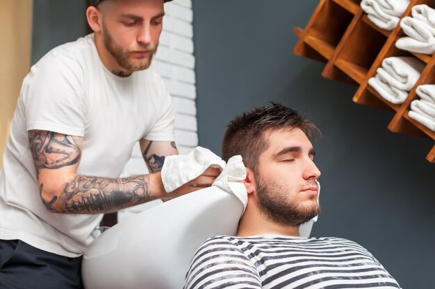 Barber enxugando a cabeça de seu cliente com uma toalha