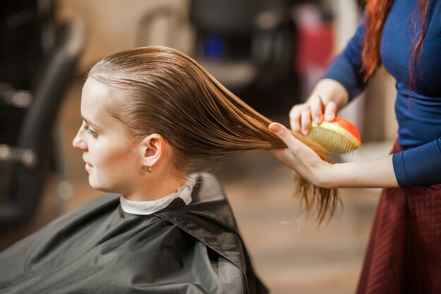 Barber Girl peine el cabello mojado en la peluquería