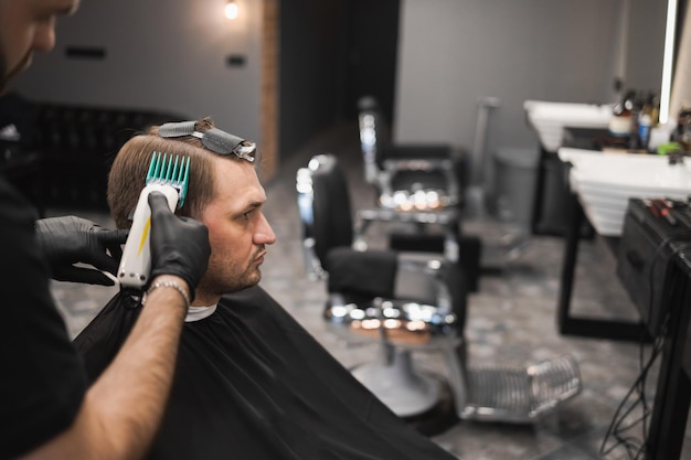 Barber master hace un corte de pelo de moda para un cliente masculino