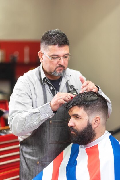 Foto barbero cortando el cabello de un cliente masculino en el salón