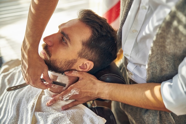 Barbero manos afeitando el cuello de su cliente en una barbería