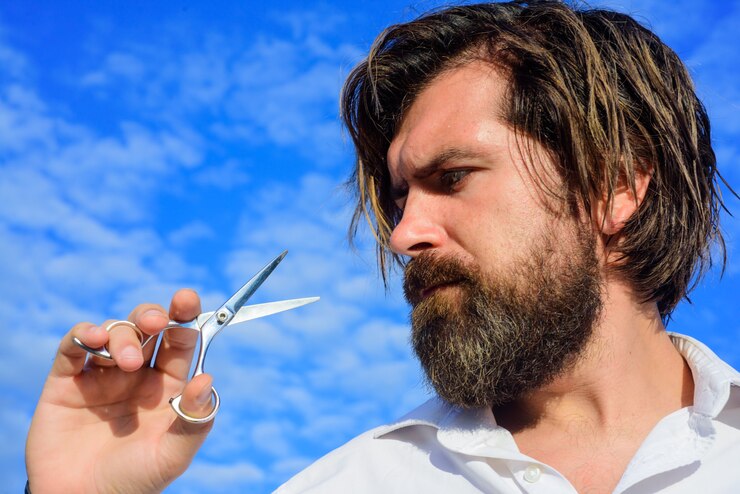 Foto barbudo barbudo com tesoura de barbeiro profissional para cuidados com a barba barbudo homem barbudo com
