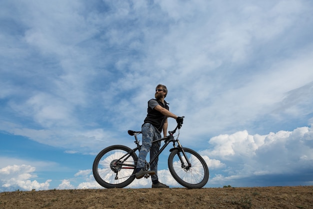 Barbudo brutal de esportes em uma bicicleta de montanha moderna. Um ciclista em um lugar deserto de sal à beira do lago.