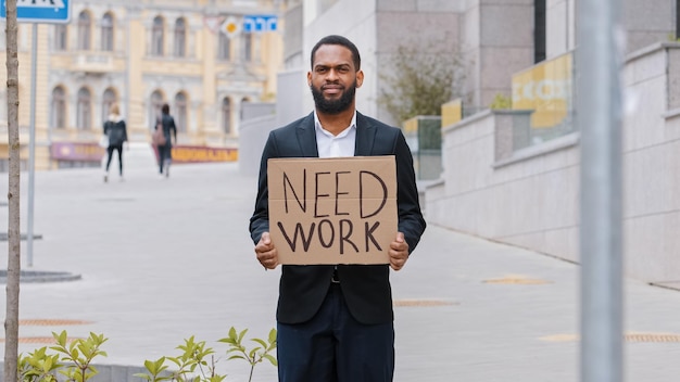 Barbudo étnico, frustrado, demitido, sem esperança, homem afro-americano trabalhador na cidade segurando cartaz precisa