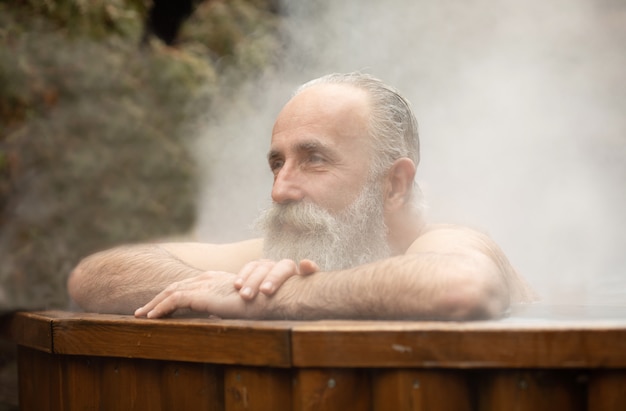 Barbudo homem sênior desfrutando de banho termal no centro de talassoterapia.