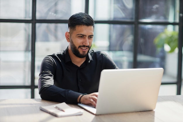 Barbudo jovem empresário trabalhando no escritório moderno Homem consultor pensando olhando no computador monitor