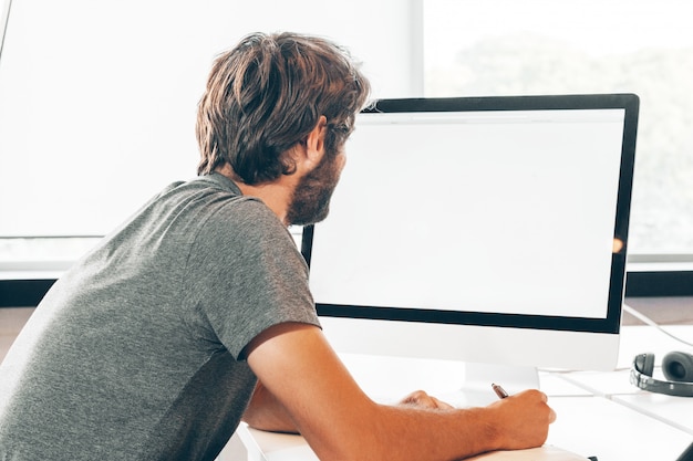 Foto barbudo jovem empresário trabalhando no escritório moderno