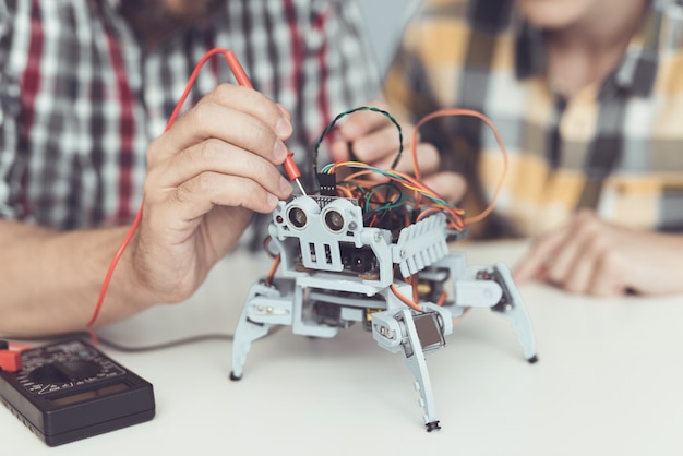 Barbudo padre e hijo construyendo robot en casa.