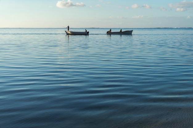Barcas de pesca que se cruzan al amanecer con el mar en calma.
