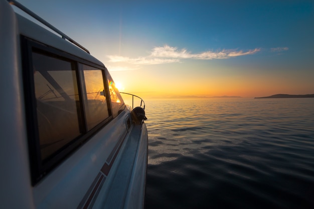 Foto barco a motor branco se movendo para o pôr do sol