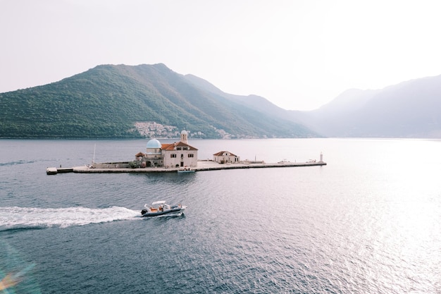 Barco a motor navega ao longo do mar passando pela ilha de gospa od skrpjela montenegro drone