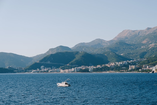 Barco a motor no mar contra a costa de Budva e as montanhas em montenegro