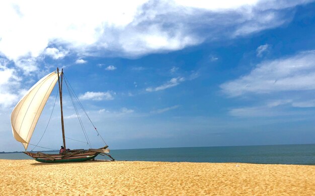 Foto barco a vela na praia contra o céu