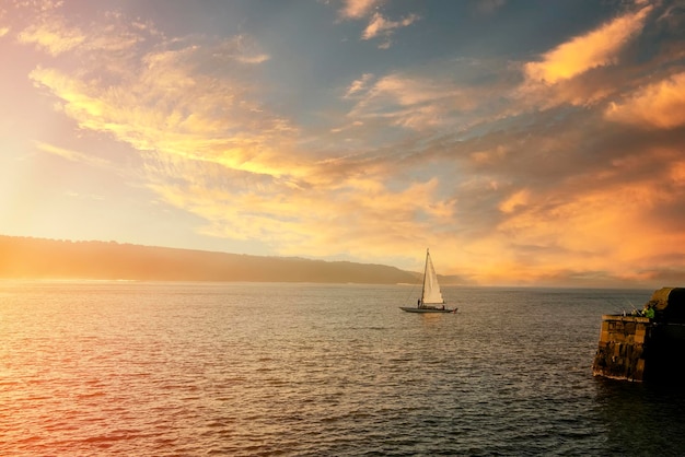 Barco à vela navegando nas ondas do mar do norte em scarborough ao pôr do sol