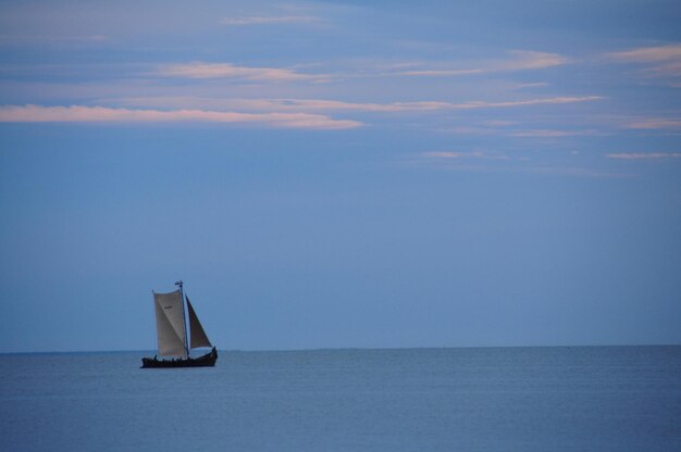 Foto barco a vela navegando no mar contra o céu durante o pôr-do-sol