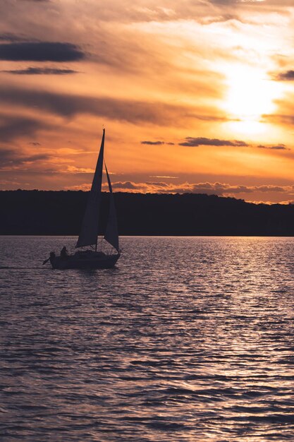Foto barco a vela navegando no mar contra o céu durante o pôr-do-sol