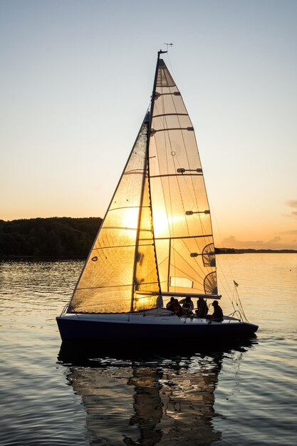 Foto barco a vela navegando no mar contra um céu claro durante o pôr-do-sol