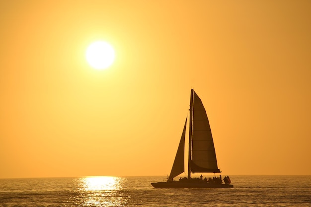 Barco a vela navegando no mar contra um céu claro durante o pôr-do-sol
