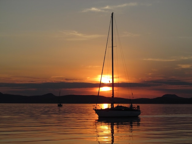 Barco a vela no lago contra o céu durante o pôr do sol