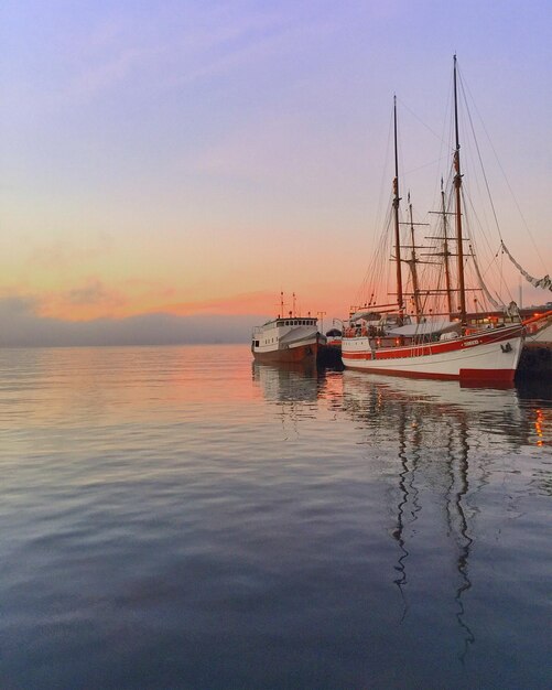 Foto barco a vela no mar ao pôr-do-sol