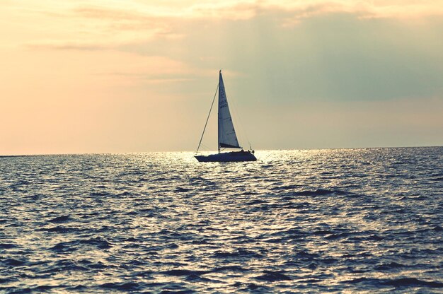 Foto barco a vela no mar ao pôr-do-sol