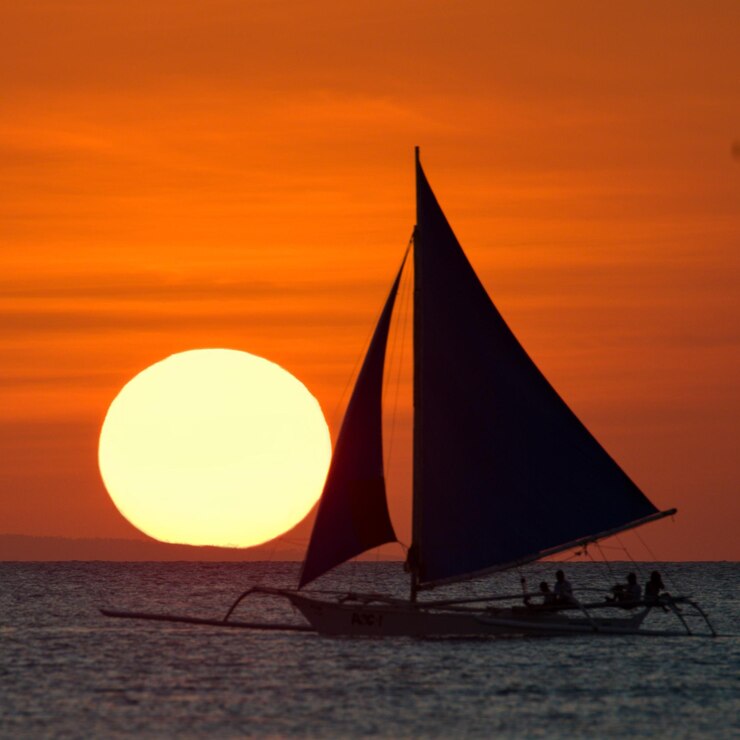 Foto barco a vela no mar contra o céu laranja