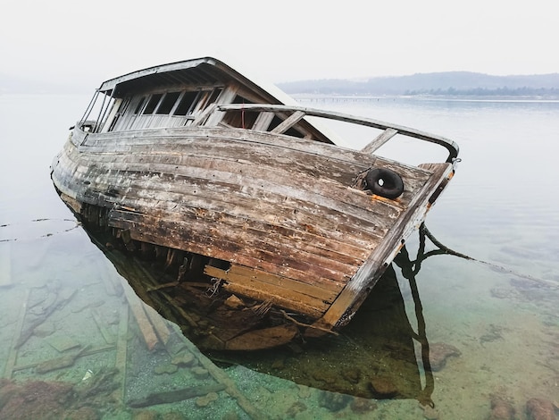 Foto barco abandonado amarrado en la orilla del mar contra el cielo