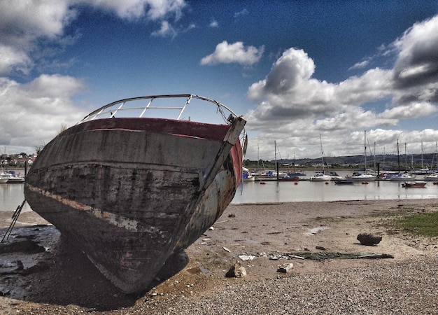 Foto barco abandonado amarrado en la playa contra el cielo