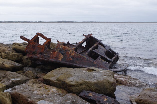 Foto barco abandonado en la orilla del mar contra el cielo