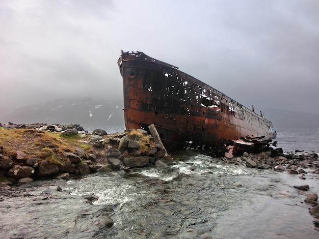 Foto un barco abandonado en la playa contra el cielo.