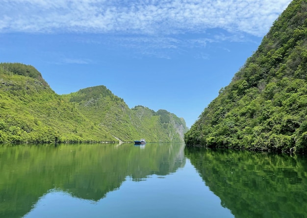 Un barco en el agua con montañas al fondo.