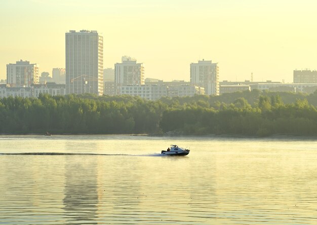 Barco en el agua. Orilla construida del gran río Ob siberiano en la niebla de la mañana