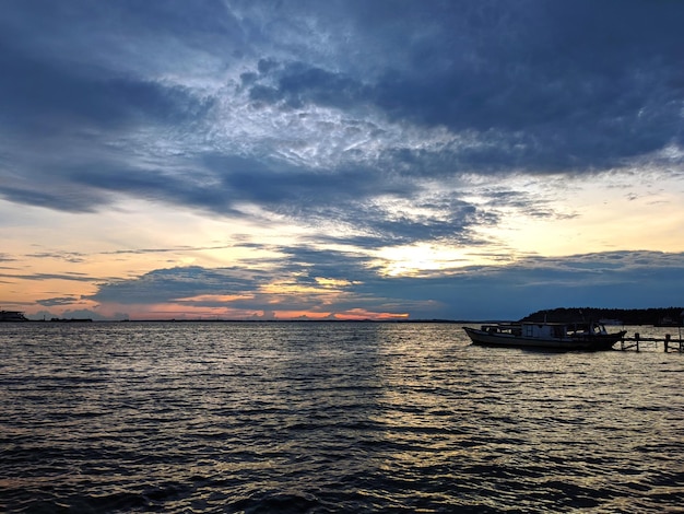 Un barco en el agua con una puesta de sol de fondo