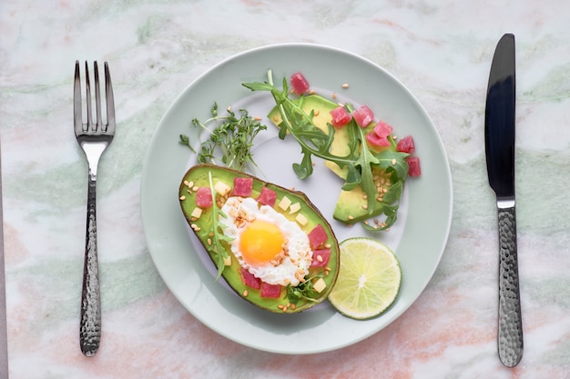 Barco de aguacate al horno con cubitos de jamón, huevo de codorniz y queso servido con ensalada de rúcula verde