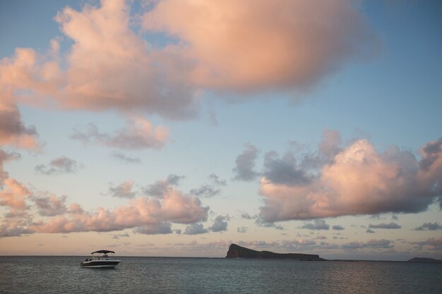 Barco al atardecer con nubes y océano azul