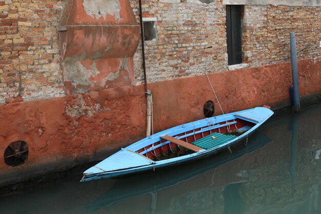 Foto barco amarrado en el canal contra una pared de ladrillo