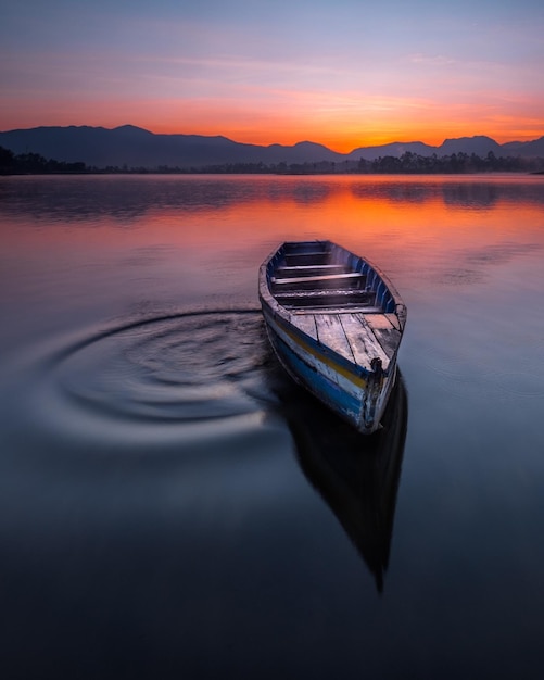 Barco amarrado en el lago contra el cielo durante la puesta de sol