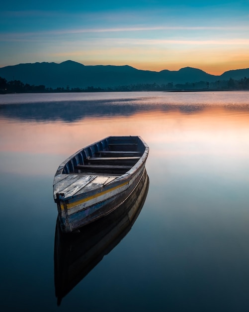 Barco amarrado en el lago contra el cielo durante la puesta de sol