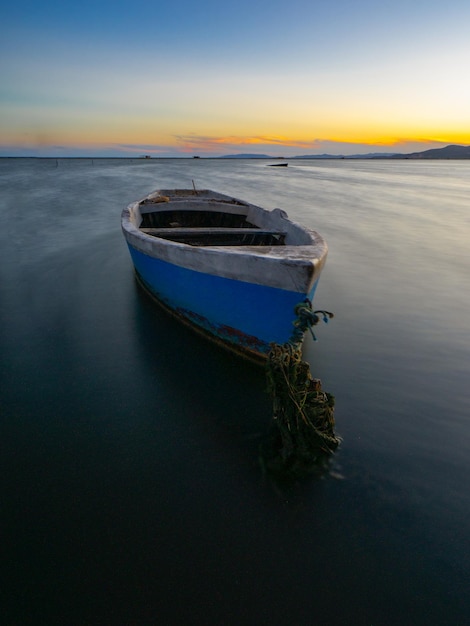 Foto barco anclado en la playa al atardecer