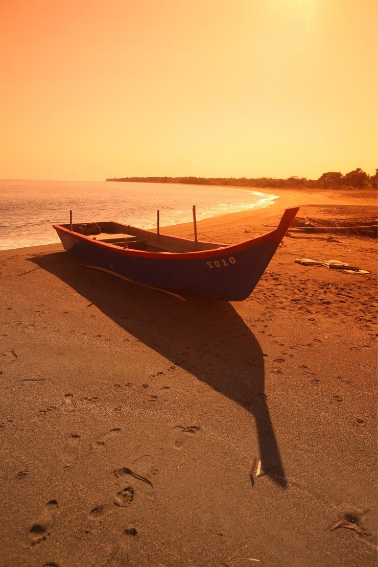 Foto barco ancorado na costa na praia contra o céu durante o pôr do sol