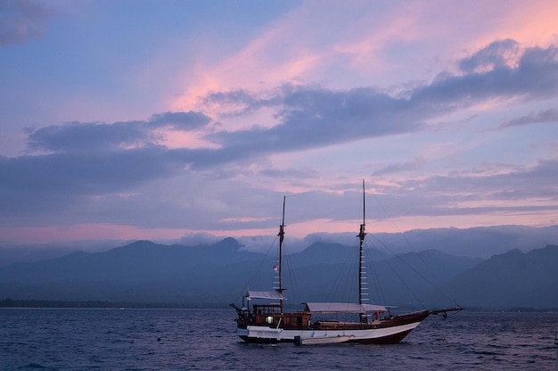 Barco ancorado no mar contra o céu durante o pôr-do-sol