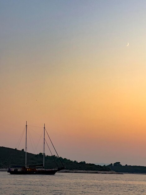 Foto un barco está atracado en la playa y la luna está en el cielo