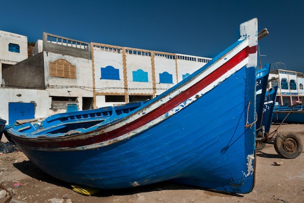 Un barco azul yace en el suelo frente a los edificios del pueblo pesquero de Tafelney