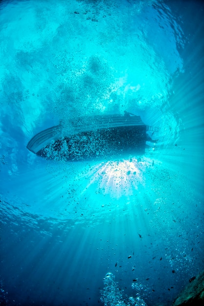 Barco de buceo desde el océano azul submarino con rayos de sol