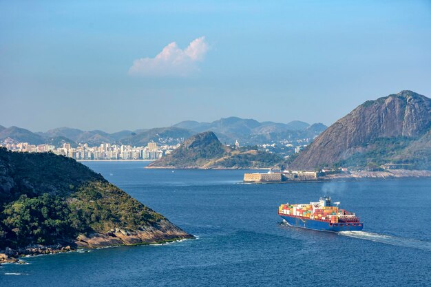 Foto barco de carga entrando en la bahía de guanabara en río de janeiro con la ciudad de niteroi en el fondo