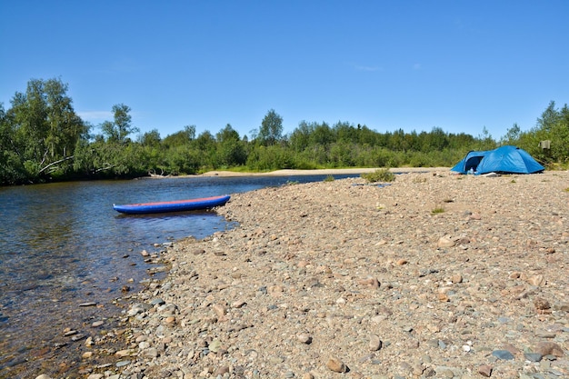 Barco y carpa en la orilla del río.