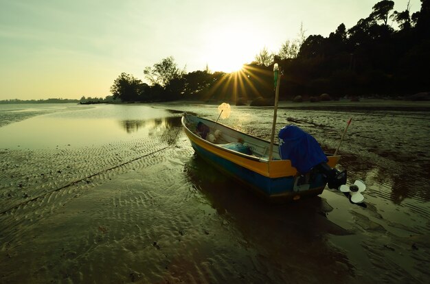 Barco cerca de la playa cuando se pone el sol.