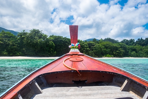 Barco de cola larga de madera frontal y mar de cristal con cielo azul