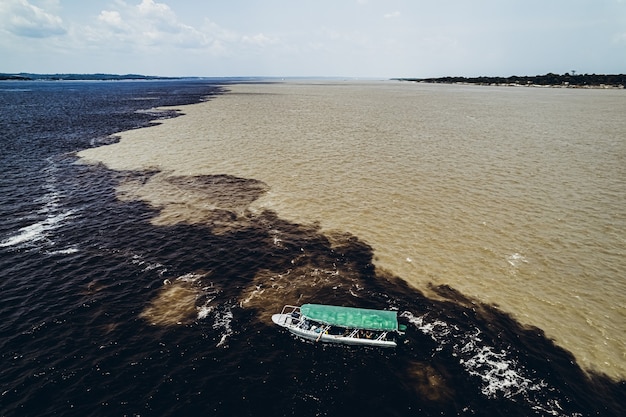 Foto barco com turistas à beira de misturar rios amazonas foto de alta qualidade